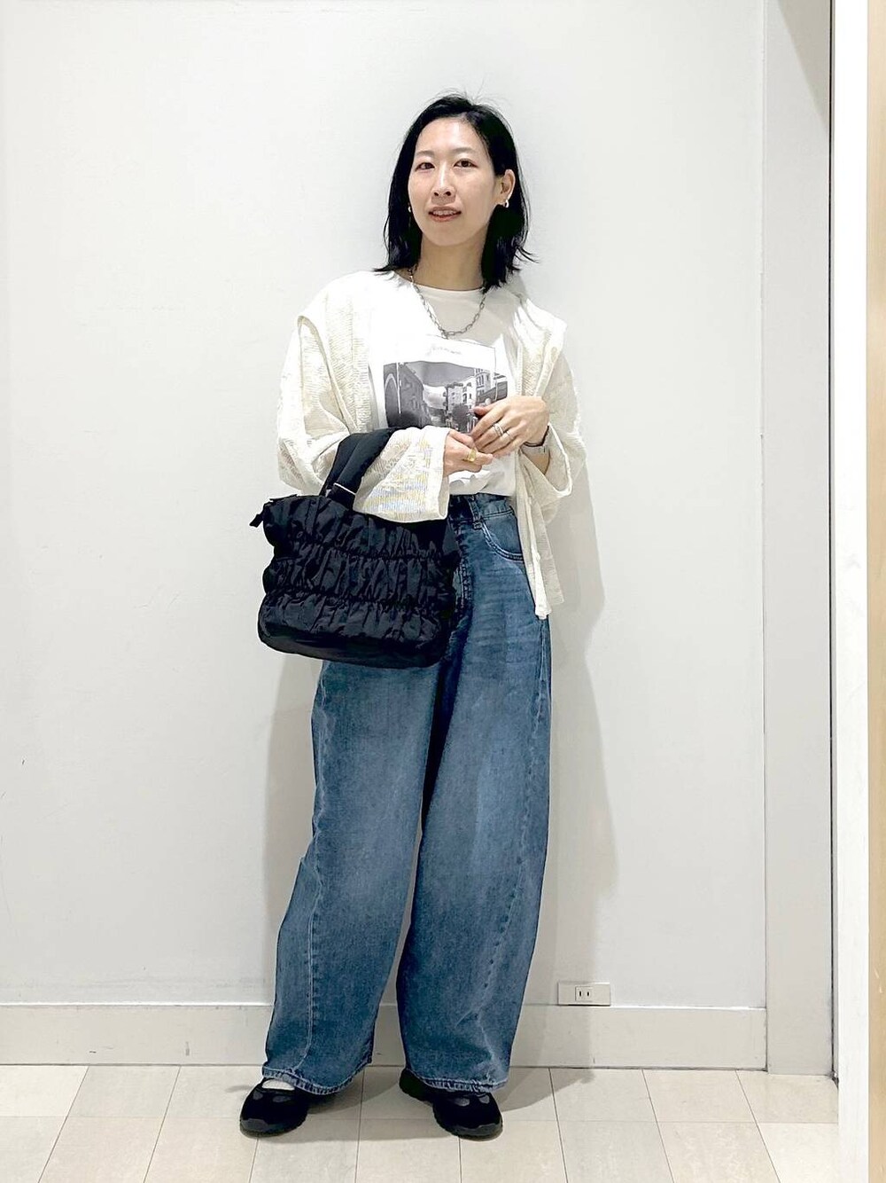 ブラック系のトートバッグ、ブルー系のデニムパンツ、ベージュ系のパーカーを着用したレディースの春コーディネートの1枚目の写真
