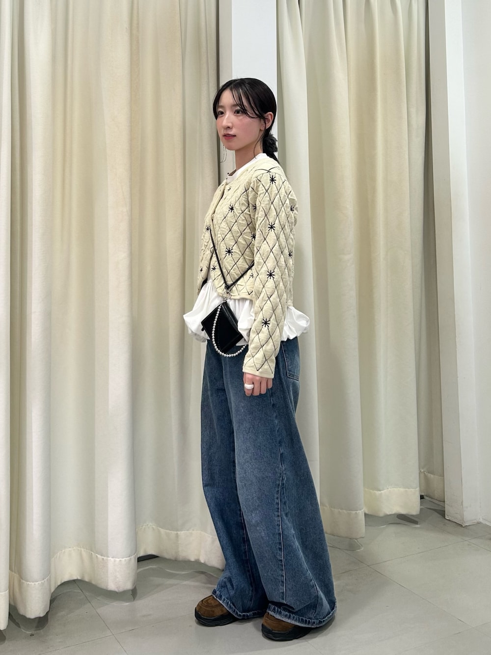 ベージュ系のニット/セーター、ホワイト系のTシャツ/カットソー、ブルー系のデニムパンツを着用したレディースの秋コーディネートの1枚目の写真