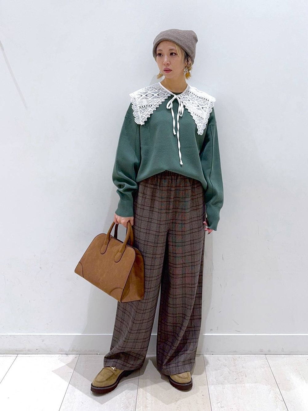 グリーン系のスウェット、ベージュ系のローファー、ベージュ系のショルダーバッグを着用したレディースの秋コーディネートの1枚目の写真