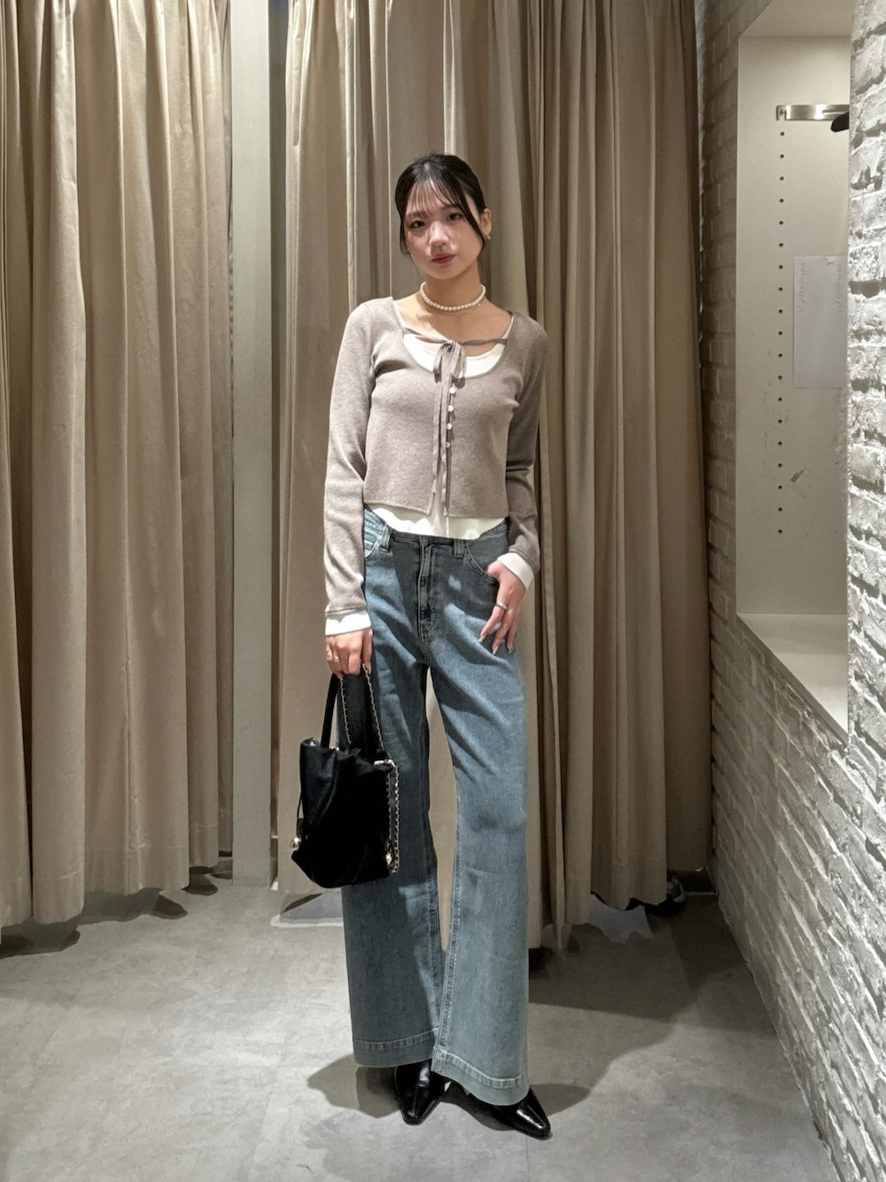 ブラウン系のニット/セーター、ブルー系のデニムパンツ、ブラック系のショルダーバッグを着用したレディースの冬コーディネートの1枚目の写真