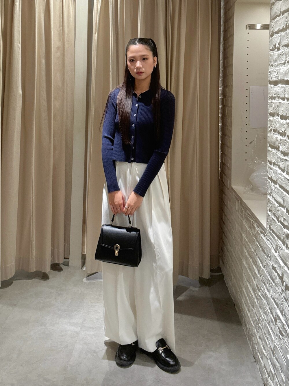 ホワイト系のスラックス、ブラック系のトートバッグを着用したレディースの秋コーディネートの1枚目の写真