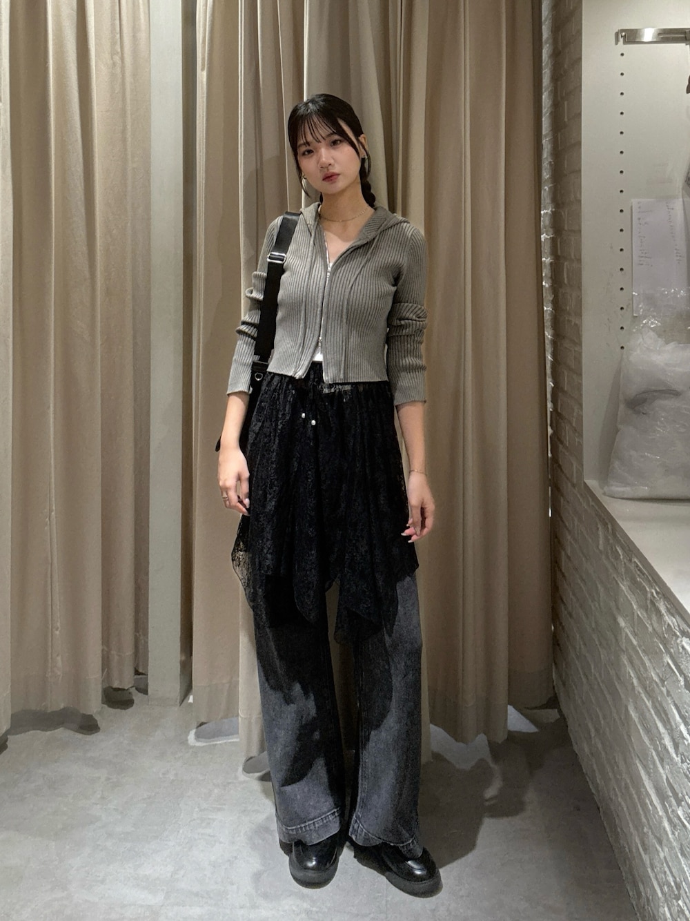 ブラウン系のニット/セーター、ブラック系のスカート、ブラック系のデニムパンツを着用したレディースの秋コーディネートの1枚目の写真