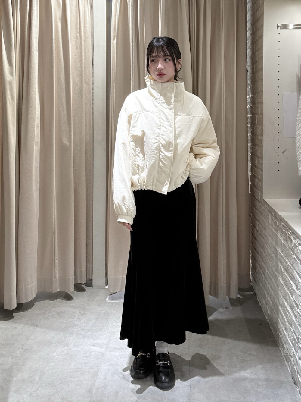ホワイト系のブルゾン、ブラック系のスカートを着用したレディースの冬コーディネートの1枚目の写真