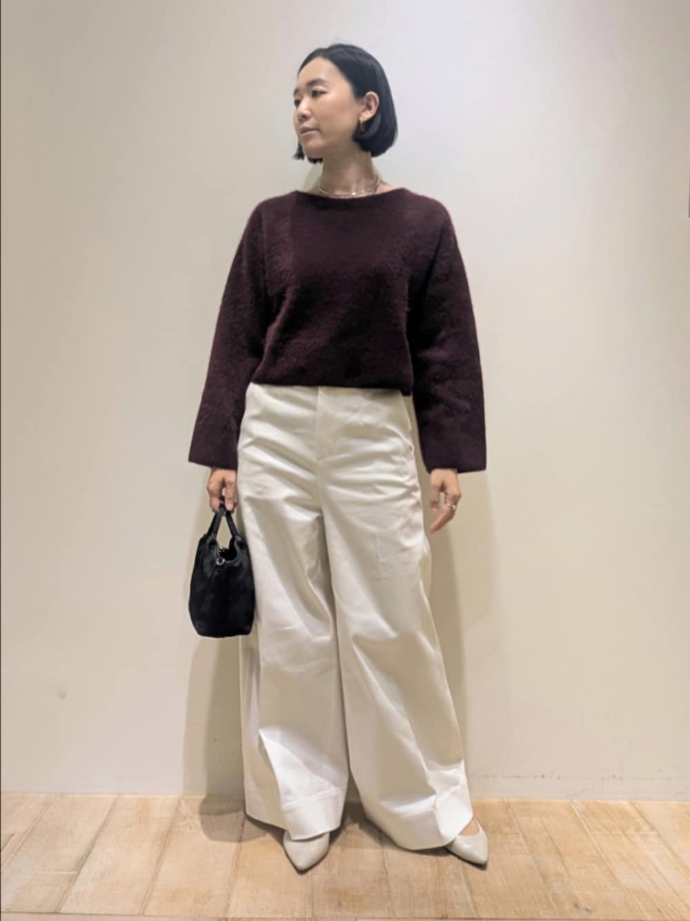 レッド系のニット/セーター、ホワイト系のデニムパンツを着用したレディースの冬コーディネートの1枚目の写真