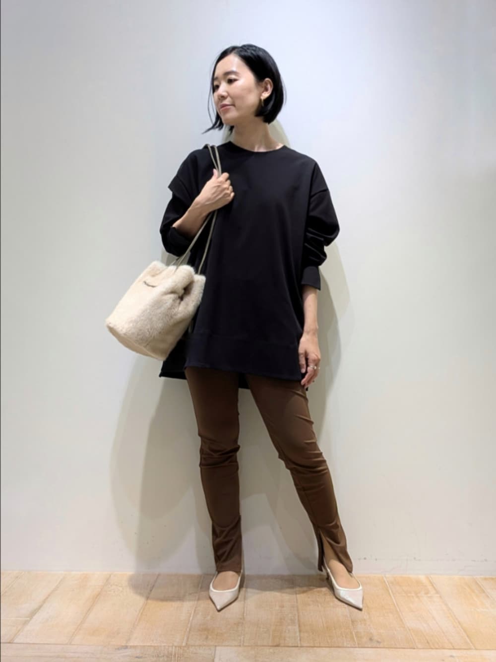 ブラック系のスウェット、ブラウン系のその他パンツ、ホワイト系のショルダーバッグを着用したレディースの秋コーディネートの1枚目の写真