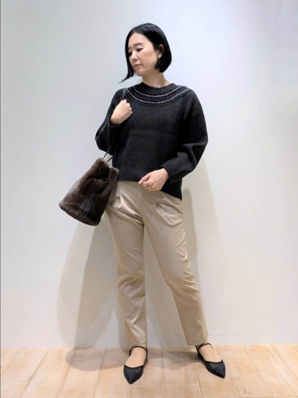 グレー系のニット/セーター、ベージュ系のその他パンツ、ブラウン系のショルダーバッグを着用したレディースの秋コーディネートの1枚目の写真