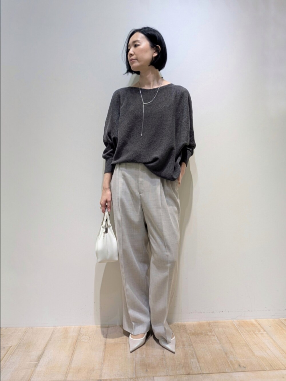 グレー系のニット/セーター、ベージュ系のその他パンツ、シルバー系のネックレスを着用したレディースの春コーディネートの1枚目の写真
