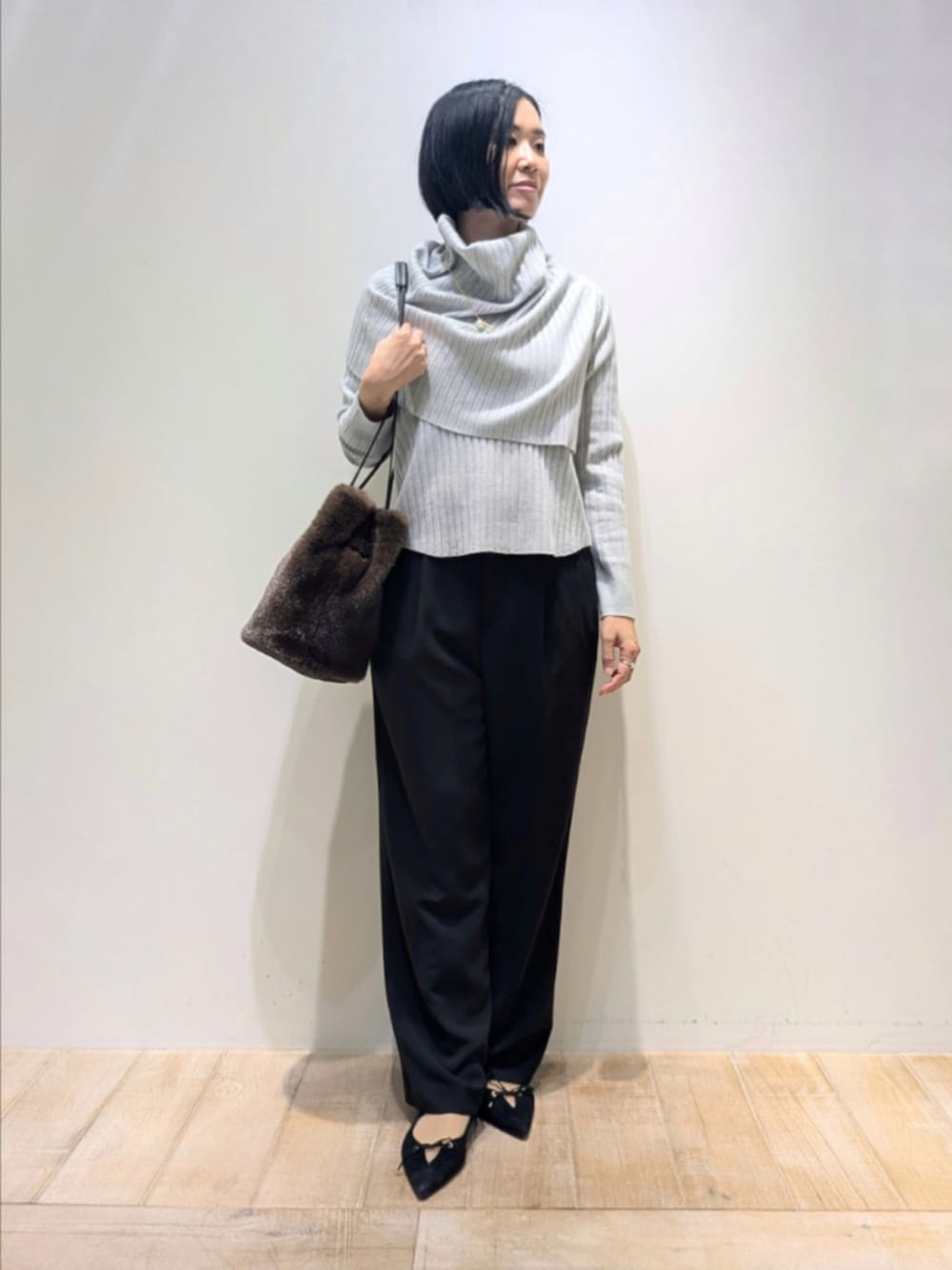 ブルー系のニット/セーター、ブラック系のその他パンツ、ブラウン系のショルダーバッグを着用したレディースの冬コーディネートの1枚目の写真