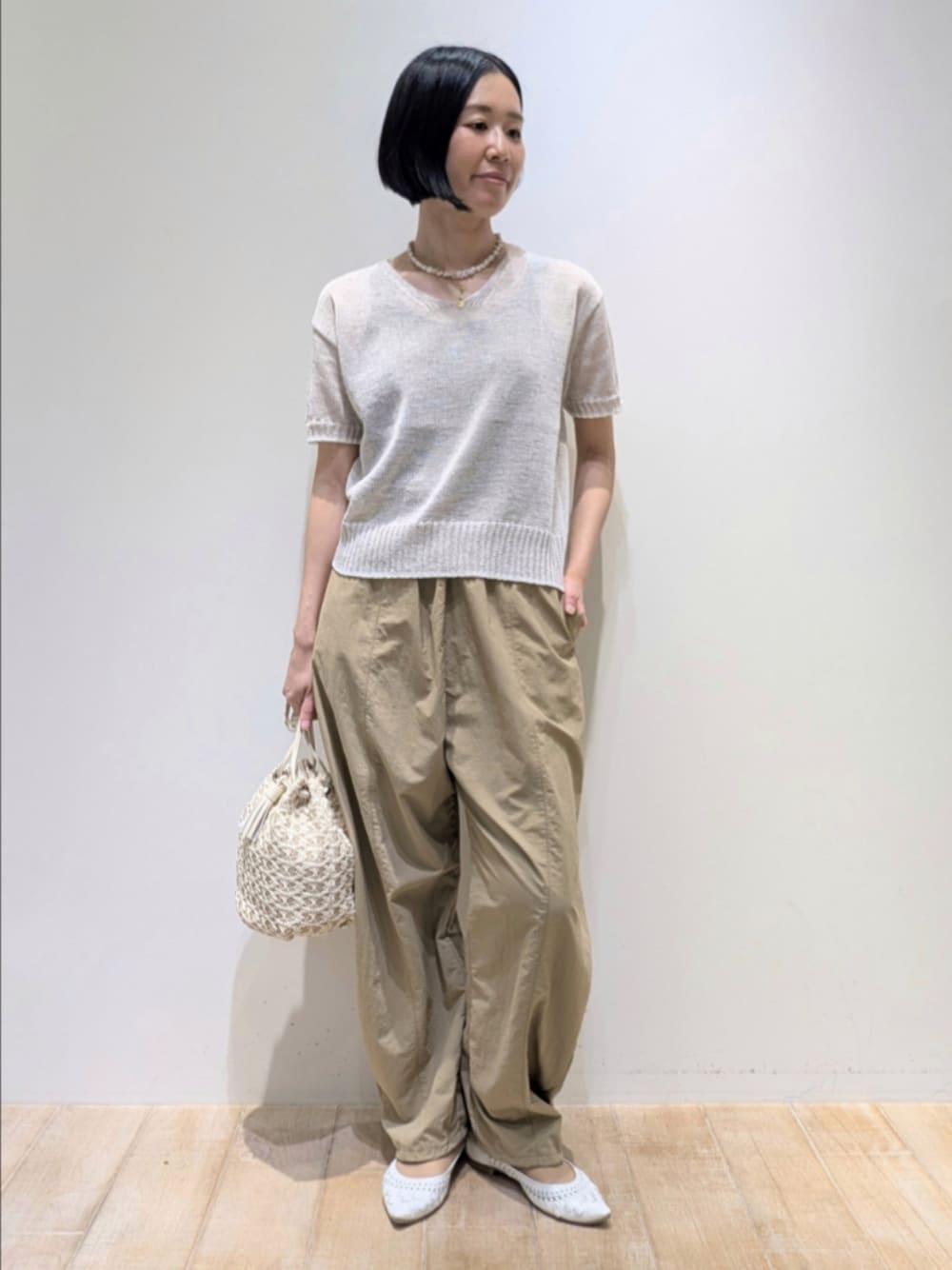 ホワイト系のニット/セーター、ベージュ系のその他パンツ、ホワイト系のショルダーバッグを着用したレディースの春コーディネートの1枚目の写真