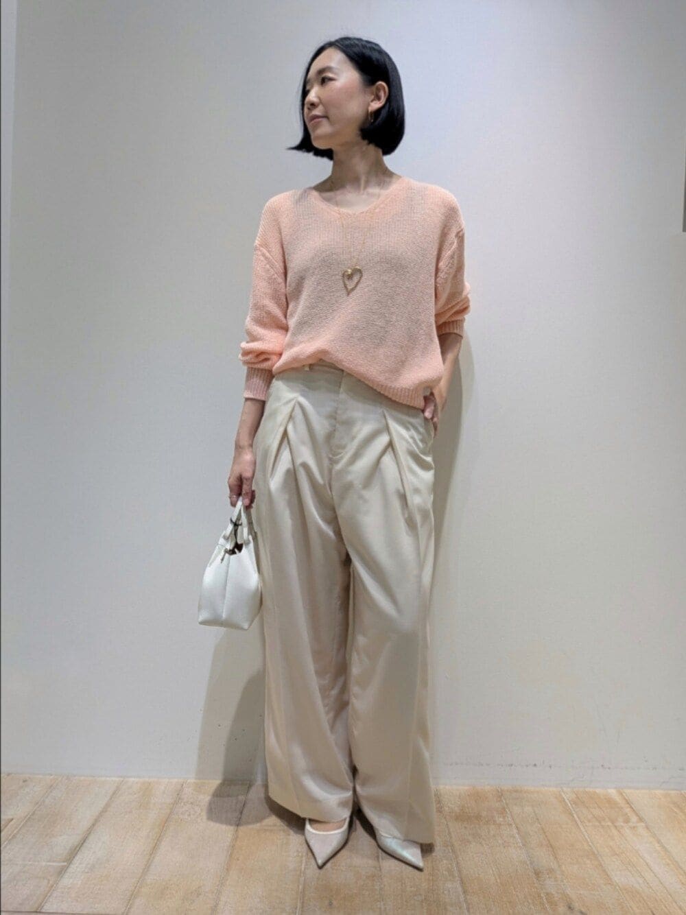 ピンク系のニット/セーター、ホワイト系のその他パンツを着用したレディースの春コーディネートの1枚目の写真