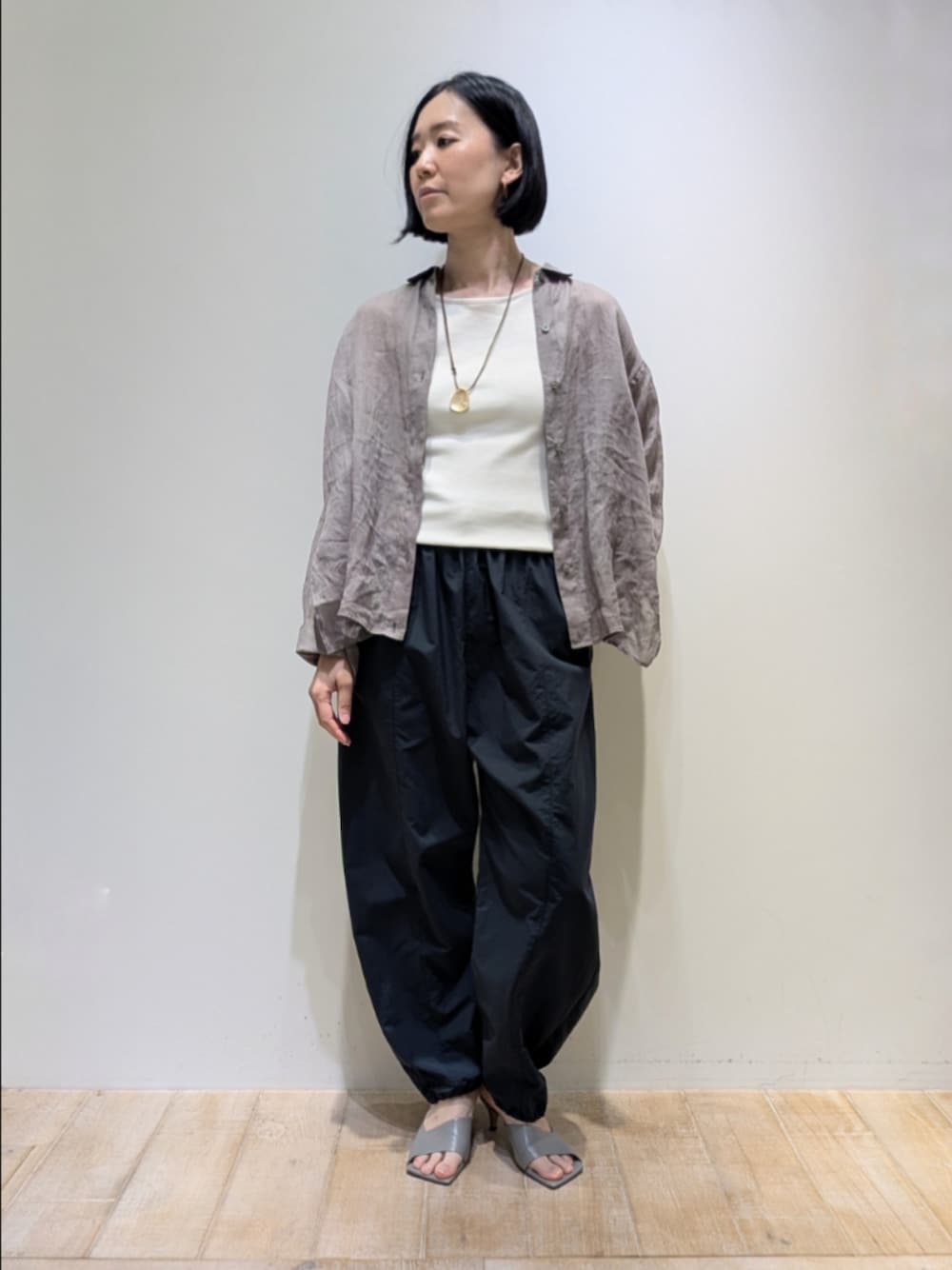 ブラウン系のシャツ/ブラウス、グレー系のその他パンツ、ゴールド系のネックレスを着用したレディースの春コーディネートの1枚目の写真