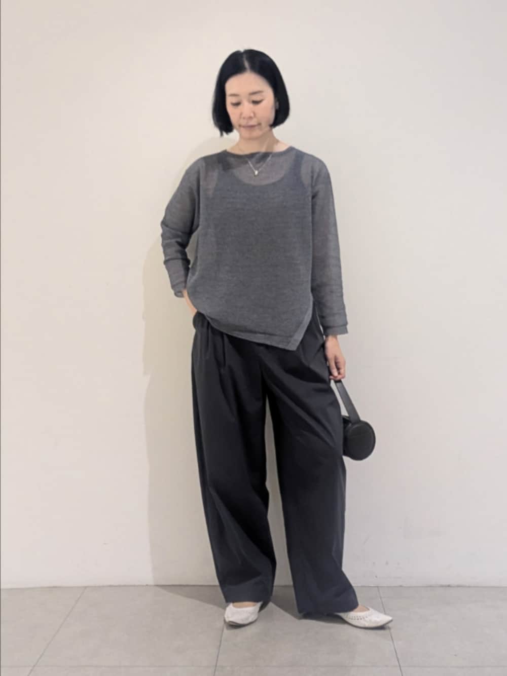 ブルー系のニット/セーター、グレー系のその他パンツ、シルバー系のネックレスを着用したレディースの夏コーディネートの1枚目の写真