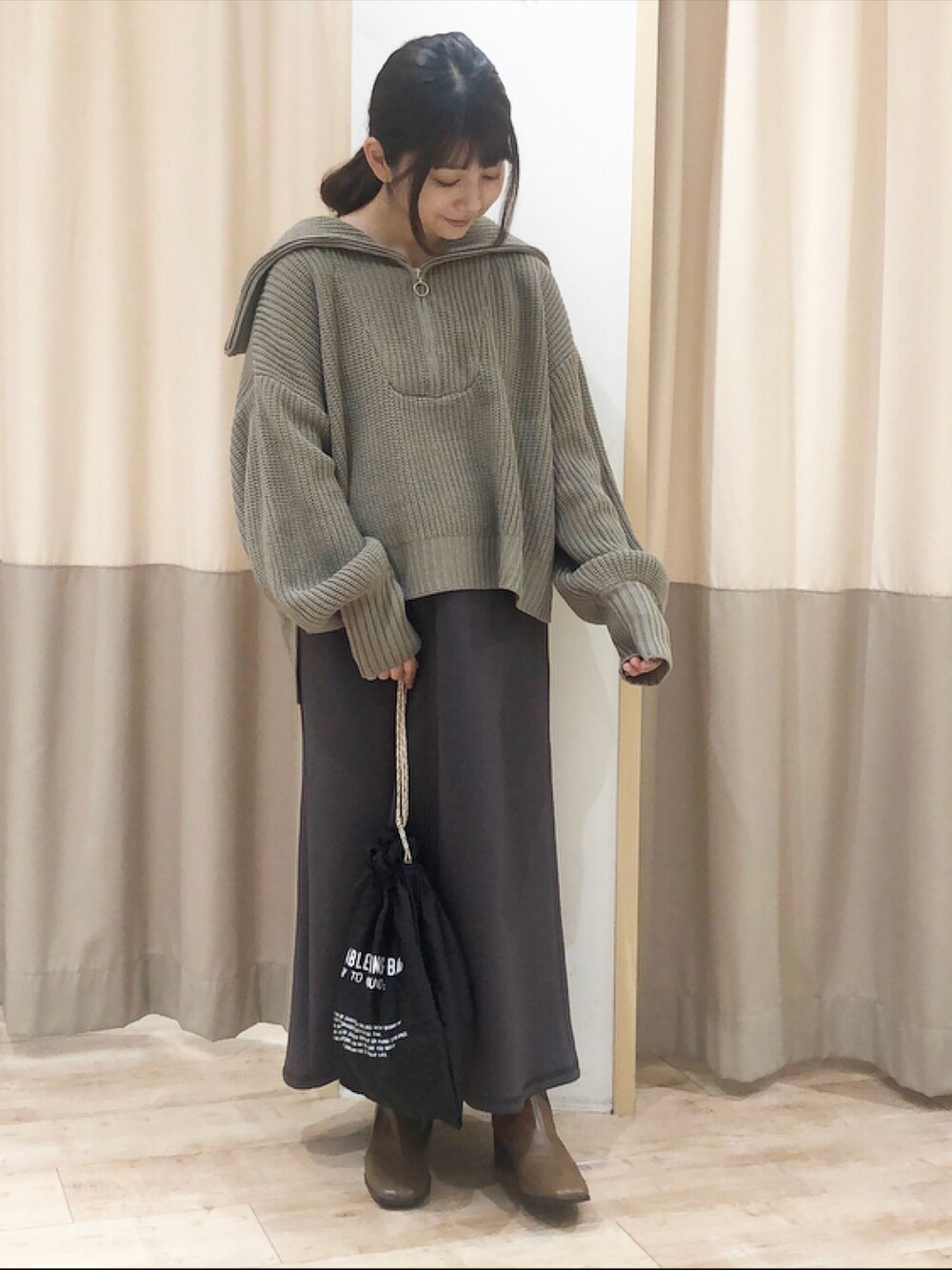 ブラウン系のニット/セーター、グレー系のスカート、ブラック系のエコバッグ/サブバッグを着用したレディースの秋コーディネートの1枚目の写真