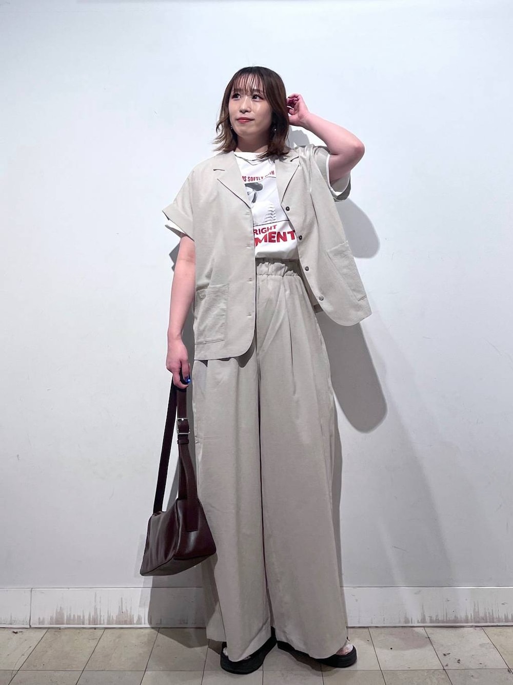 ブラウン系のショルダーバッグ、ベージュ系のその他パンツ、ホワイト系のTシャツ/カットソーを着用したレディースの夏コーディネートの1枚目の写真