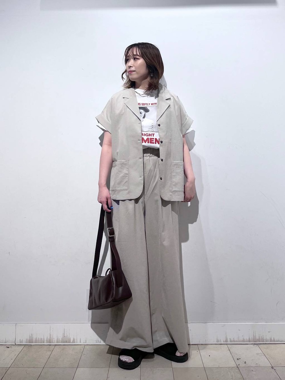 ブラウン系のショルダーバッグ、ホワイト系のTシャツ/カットソー、ブラック系のサンダルを着用したレディースの春コーディネートの1枚目の写真