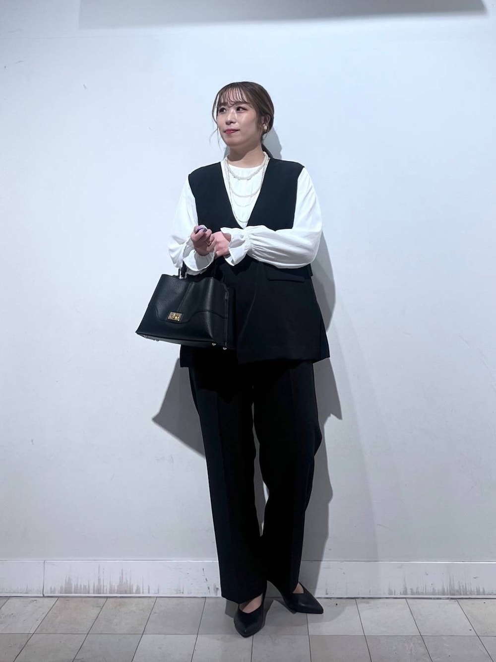 ブラック系のパンプス、ブルー系のセットアップ、ブラック系のショルダーバッグを着用したレディースの冬コーディネートの1枚目の写真