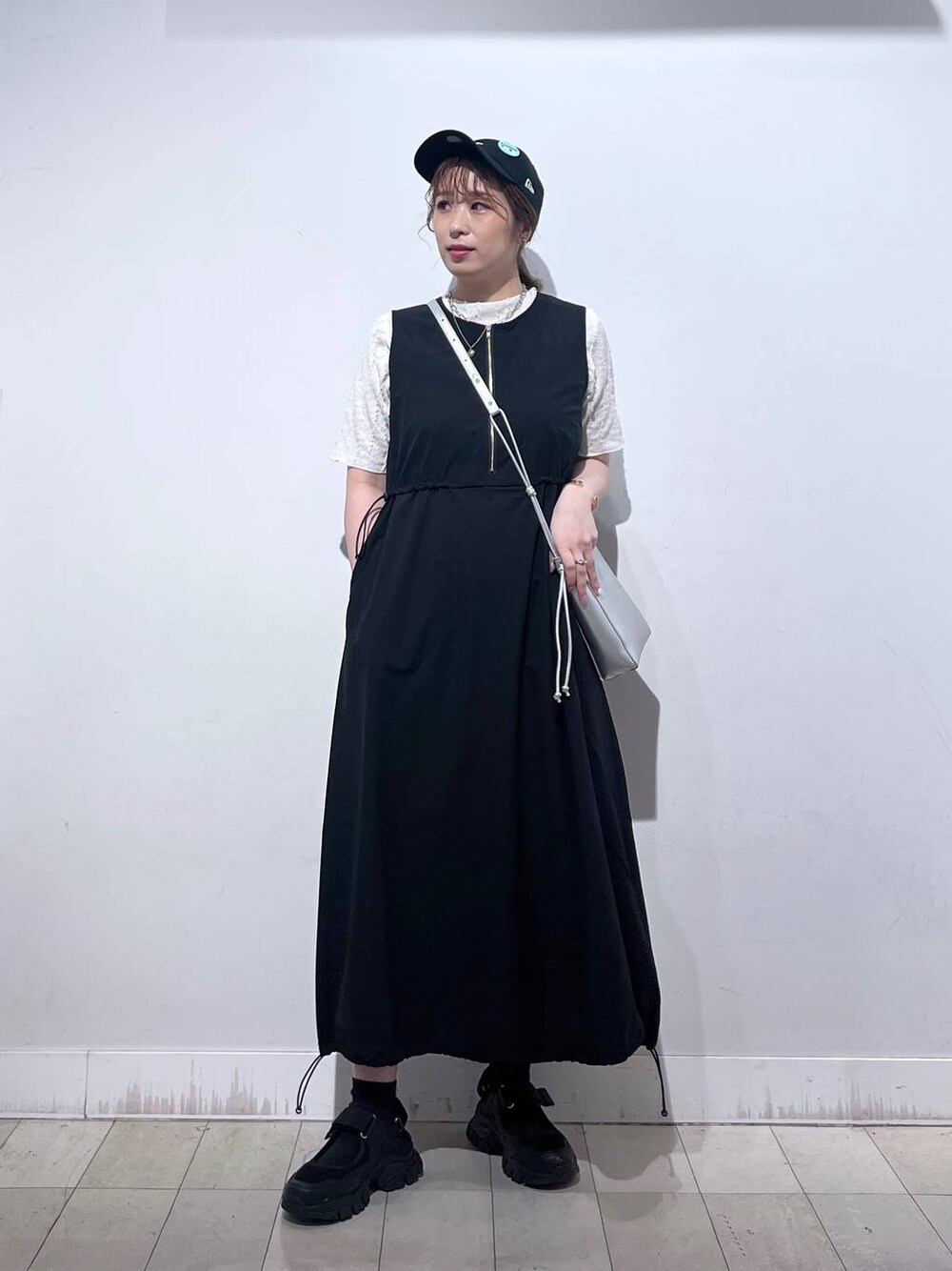 ブラック系のスニーカー、シルバー系のショルダーバッグ、ベージュ系のTシャツ/カットソーを着用したレディースの夏コーディネートの1枚目の写真