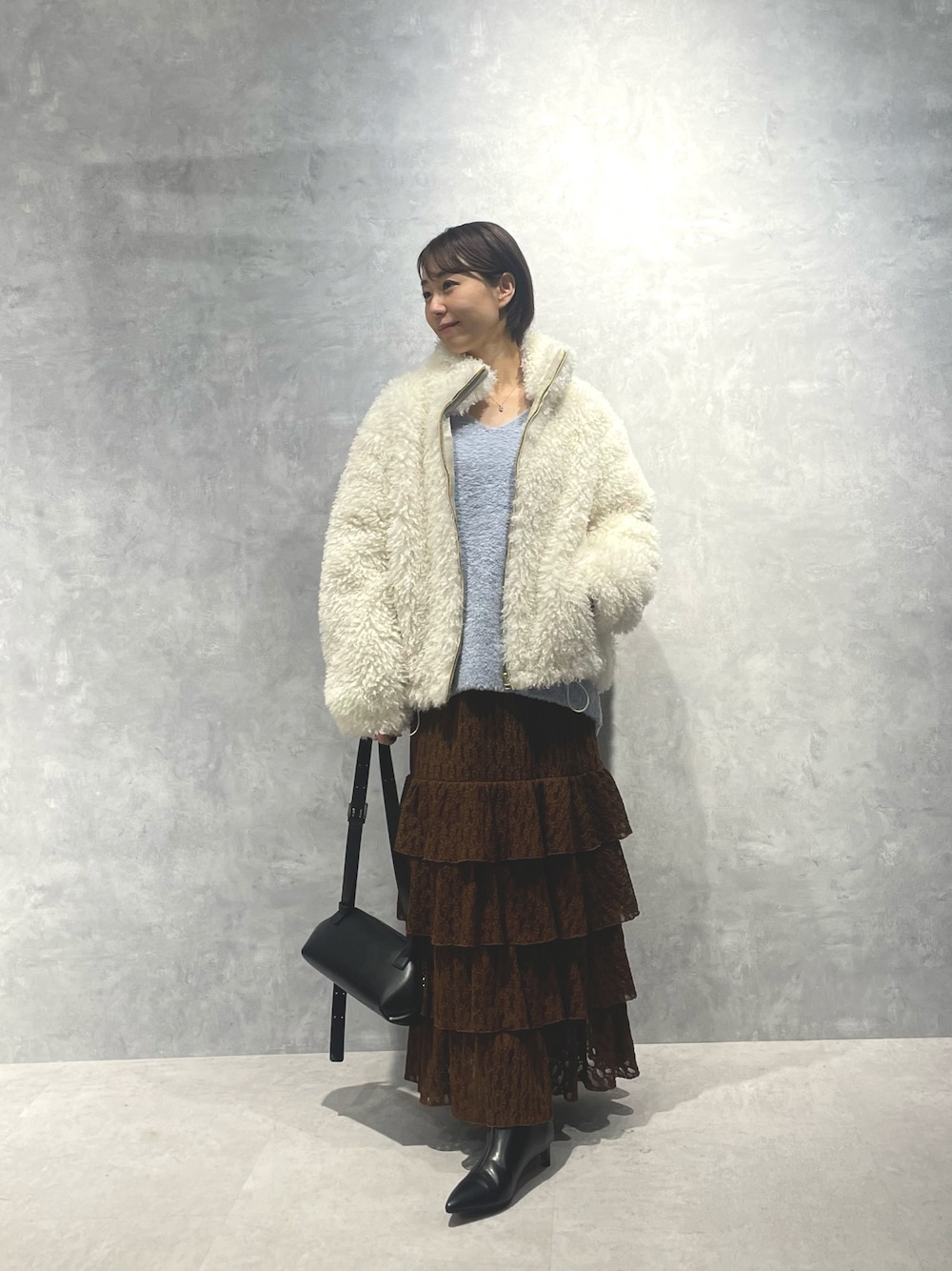 ホワイト系のブルゾン、ブルー系のニット/セーター、ブラウン系のスカートを着用したレディースの冬コーディネートの1枚目の写真