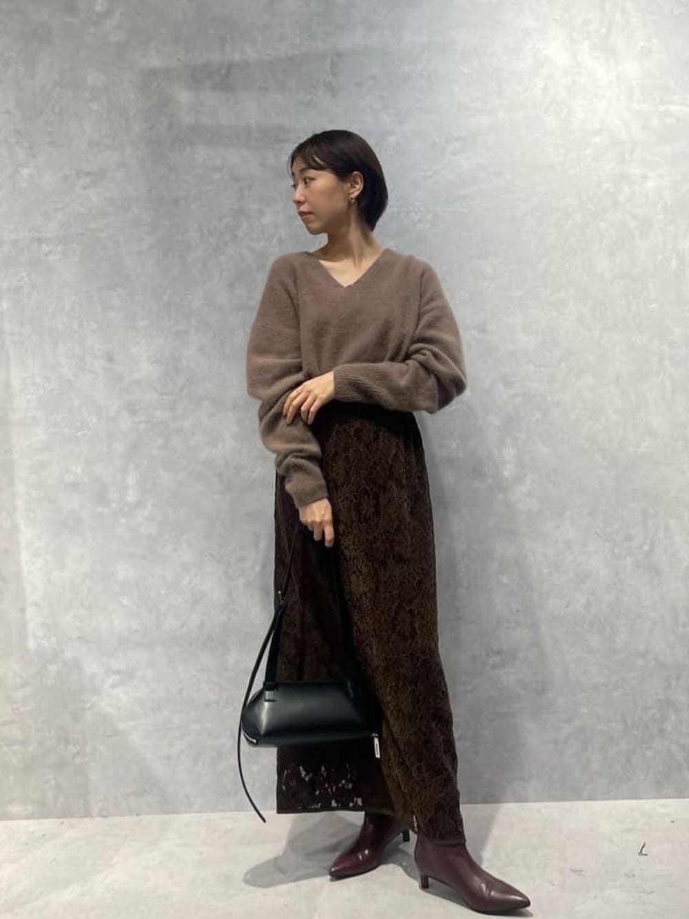 ブラウン系のニット/セーター、レッド系のブーツ、ブラウン系のスカートを着用したレディースの秋コーディネートの1枚目の写真