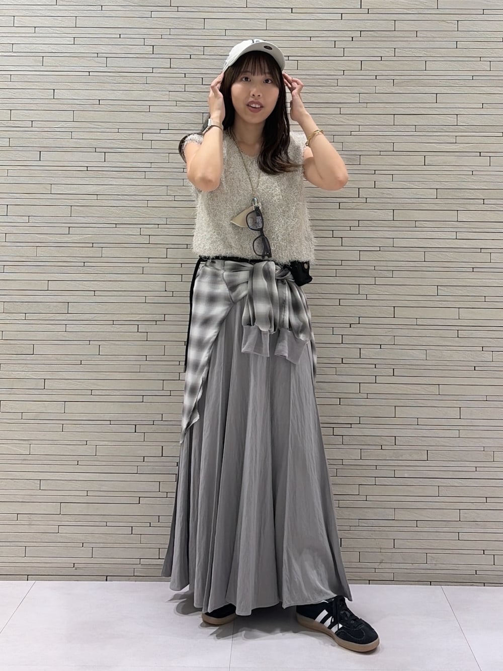 グレー系のスカート、グレー系のシャツ/ブラウス、ベージュ系のニット/セーターを着用したレディースの秋コーディネートの1枚目の写真