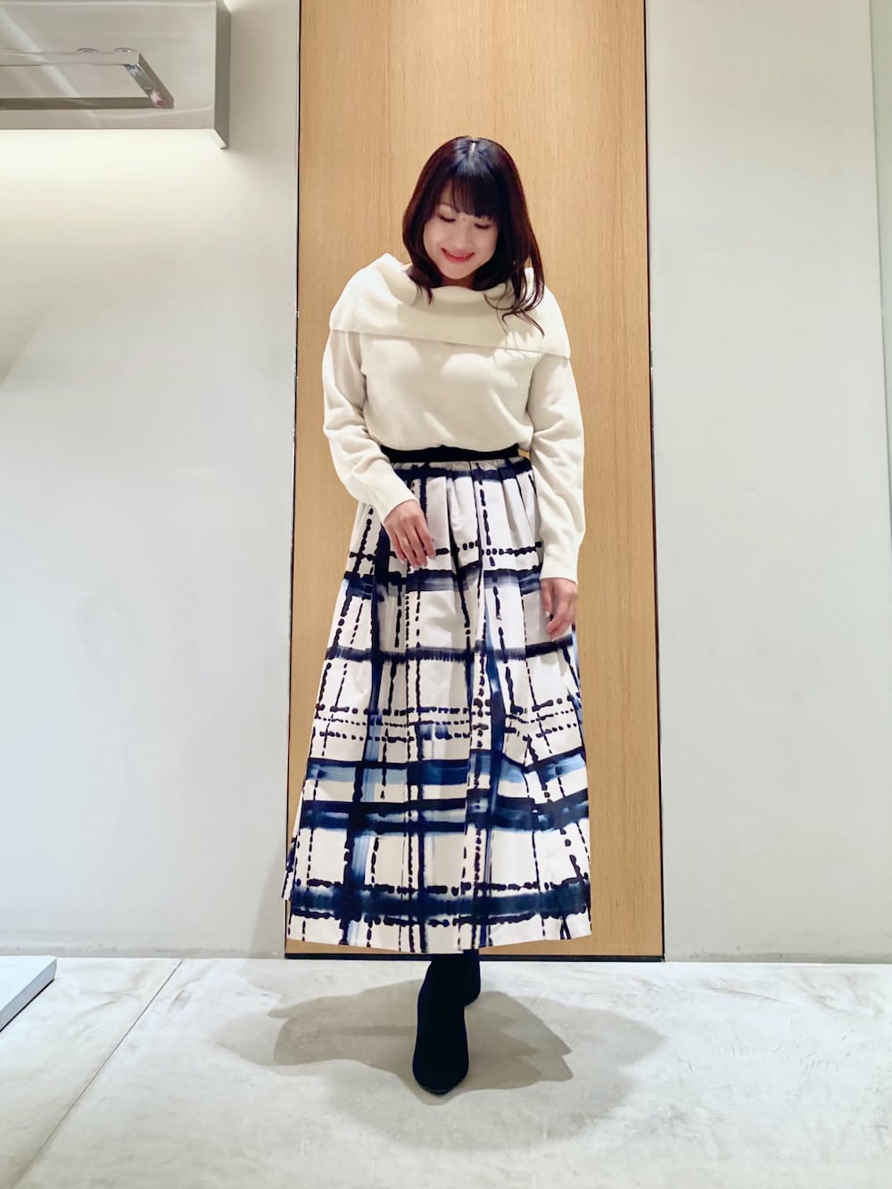 ホワイト系のニット/セーター、ホワイト系のスカート、ブラック系のイヤリングを着用したレディースの秋コーディネートの1枚目の写真