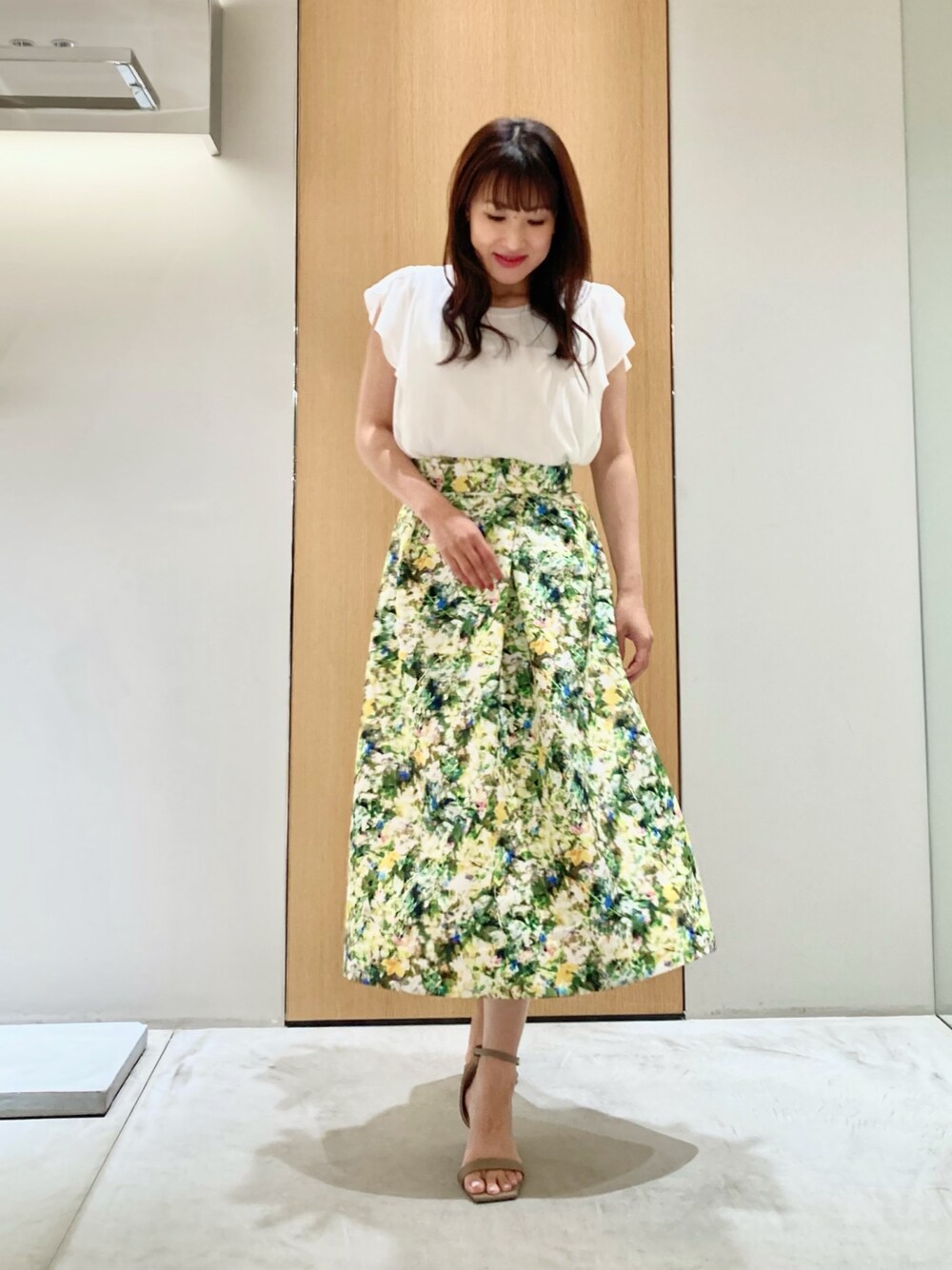 ホワイト系のその他トップス、グリーン系のスカート、ゴールド系のイヤリングを着用したレディースの夏コーディネートの1枚目の写真