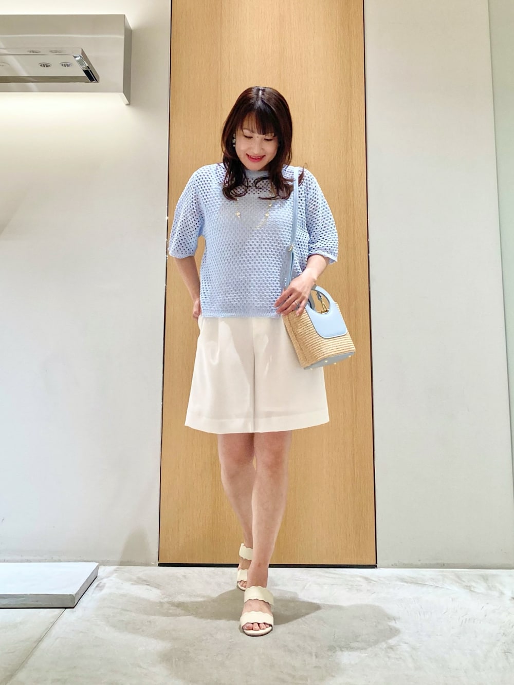 ブルー系のニット/セーター、ホワイト系のその他パンツ、ブルー系のハンドバッグを着用したレディースの夏コーディネートの1枚目の写真