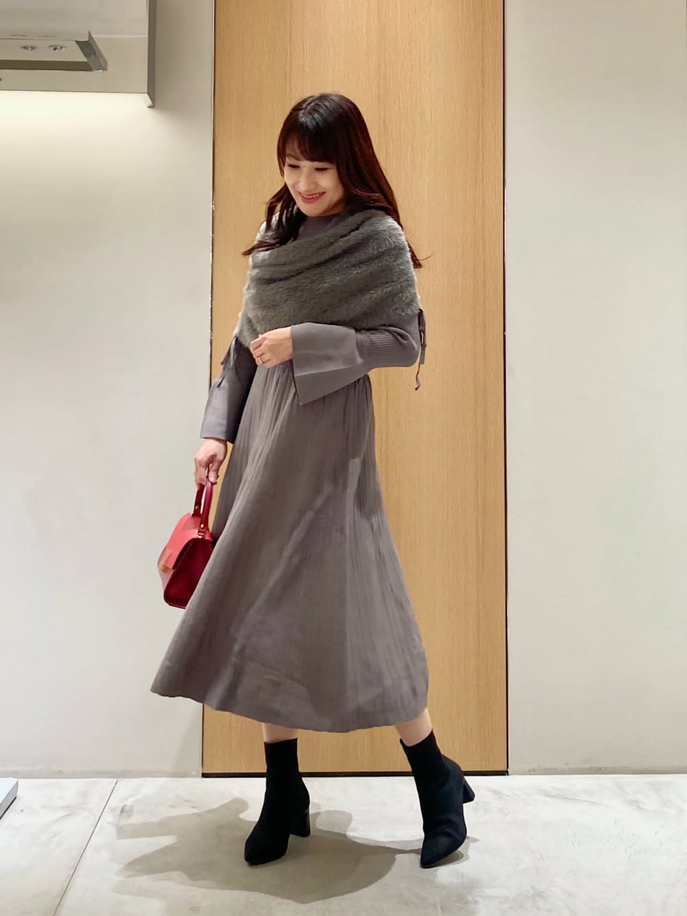 グレー系のワンピース、レッド系のハンドバッグを着用したレディースの秋コーディネートの1枚目の写真