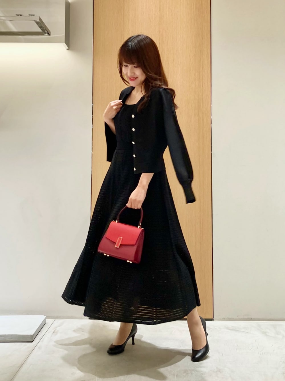 ブラック系のカーディガン/ボレロ、ブラック系のワンピース、レッド系のハンドバッグを着用したレディースの秋コーディネートの1枚目の写真