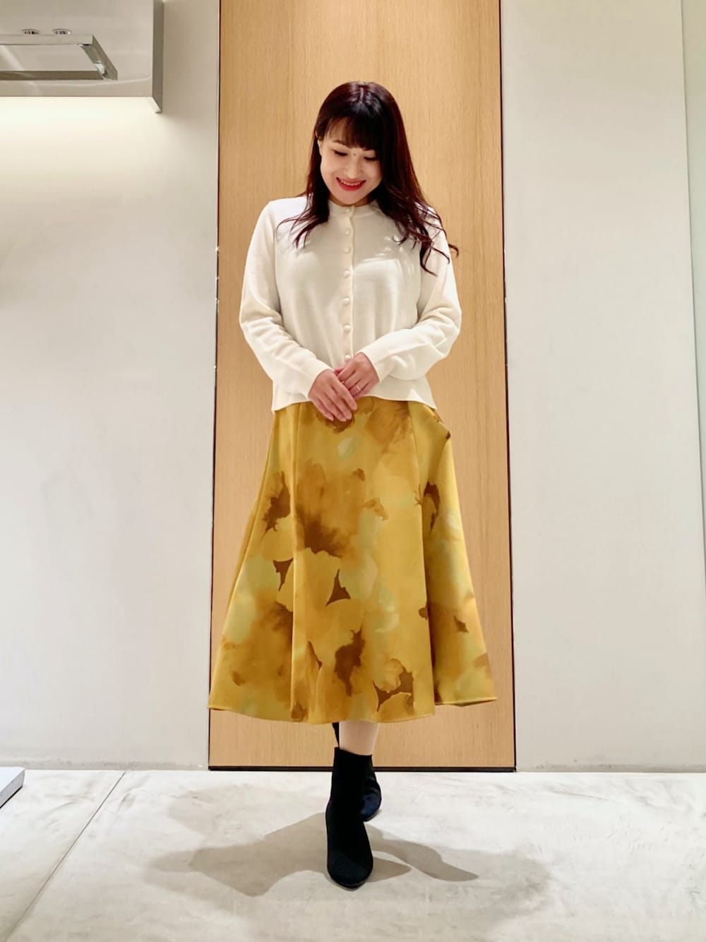 ホワイト系のカーディガン/ボレロ、イエロー系のスカートを着用したレディースの秋コーディネートの1枚目の写真