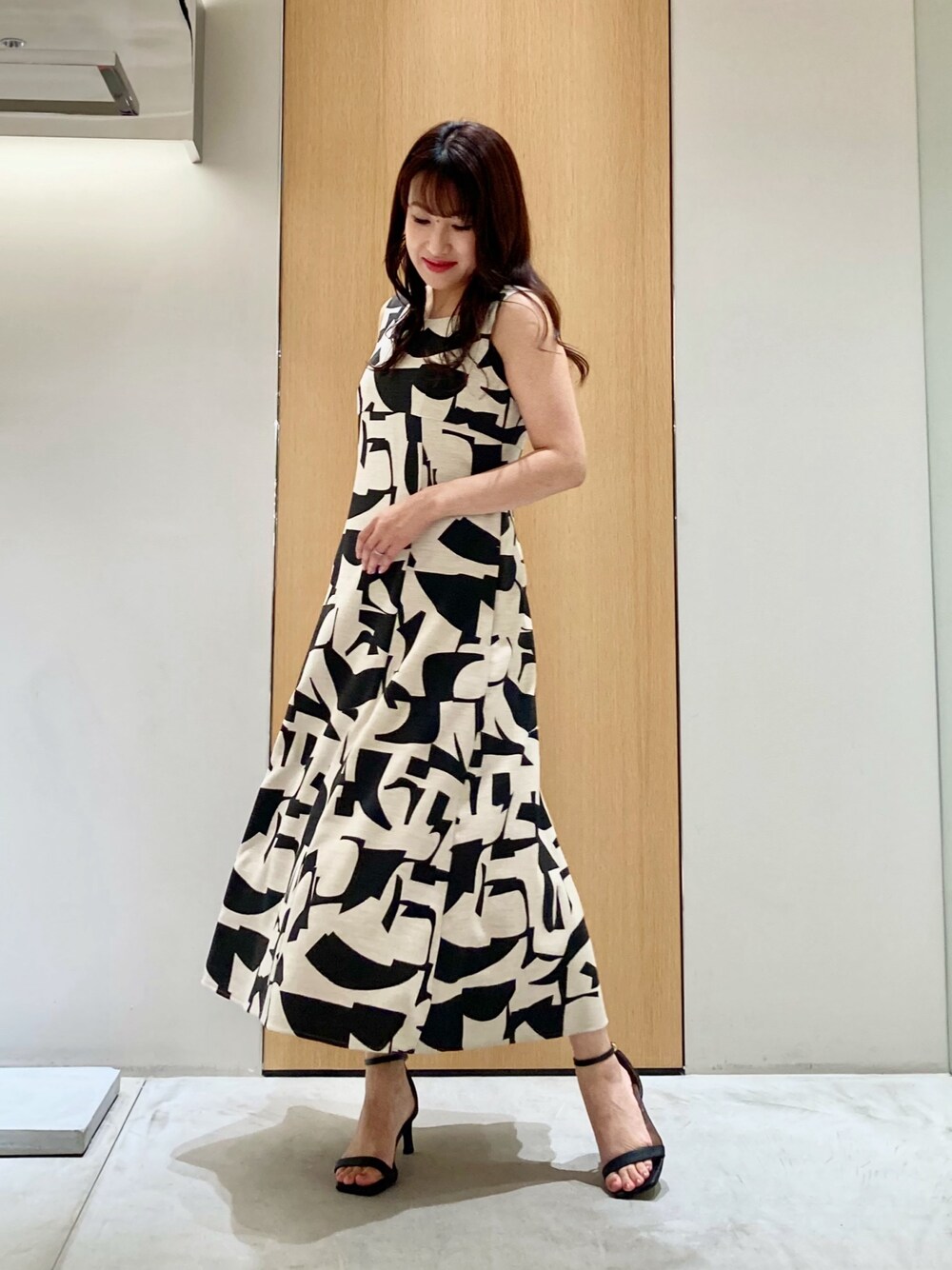 ベージュ系のワンピース、ゴールド系のイヤリングを着用したレディースの夏コーディネートの1枚目の写真