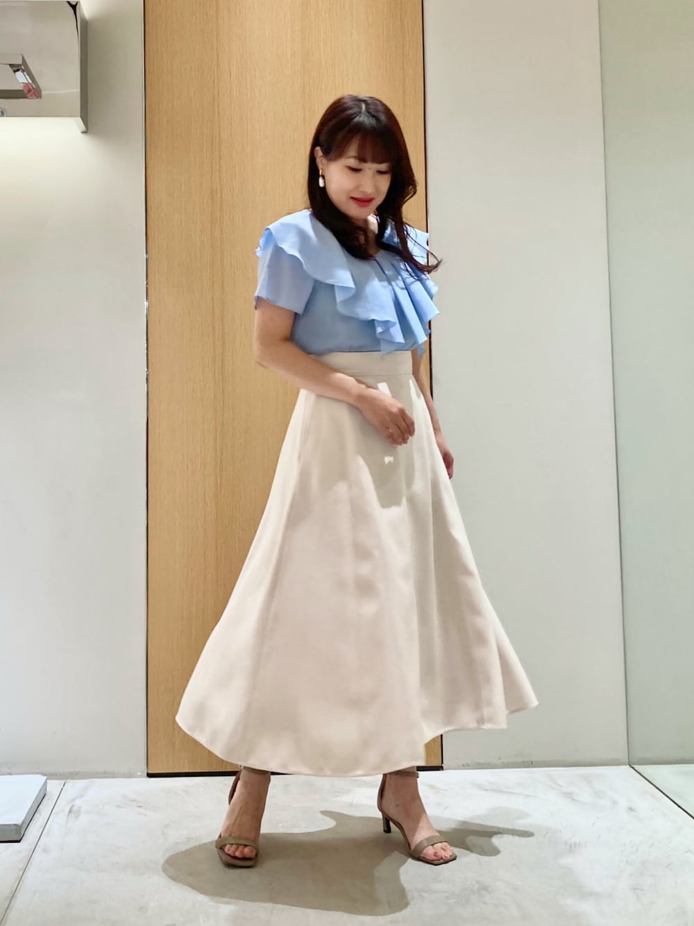 ブルー系のシャツ/ブラウス、ベージュ系のスカート、ホワイト系のイヤリングを着用したレディースの夏コーディネートの1枚目の写真