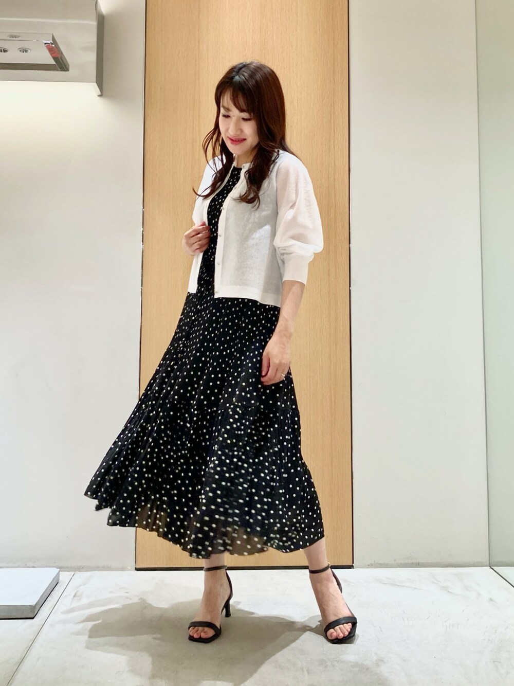ホワイト系のカーディガン/ボレロ、ブラック系のワンピース、ホワイト系のイヤリングを着用したレディースの夏コーディネートの1枚目の写真