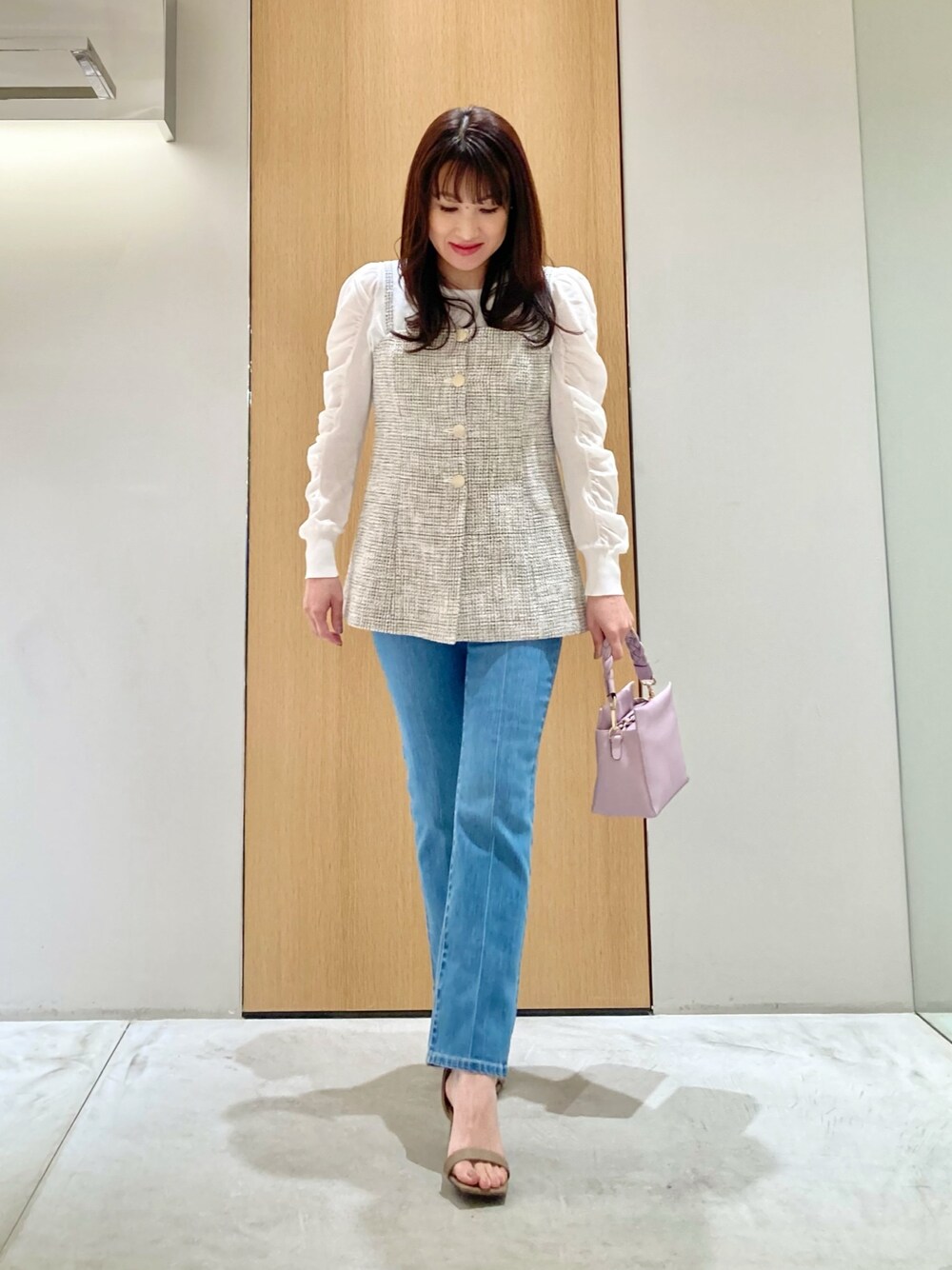 ホワイト系のニット/セーター、ホワイト系のベスト、ブルー系のデニムパンツを着用したレディースの春コーディネートの1枚目の写真