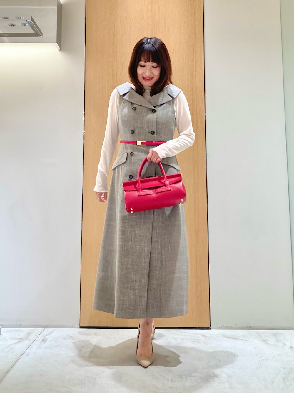ベージュ系のワンピース、ホワイト系のTシャツ/カットソー、レッド系のベルトを着用したレディースの秋コーディネートの1枚目の写真