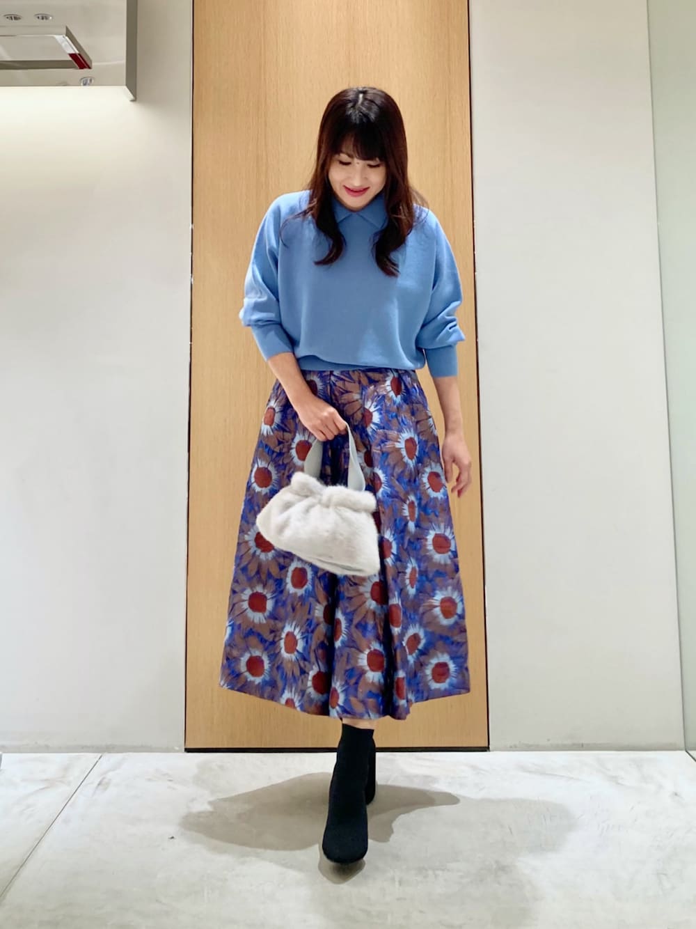 ブルー系のニット/セーター、ブルー系のハンドバッグ、ブルー系のスカートを着用したレディースの秋コーディネートの1枚目の写真