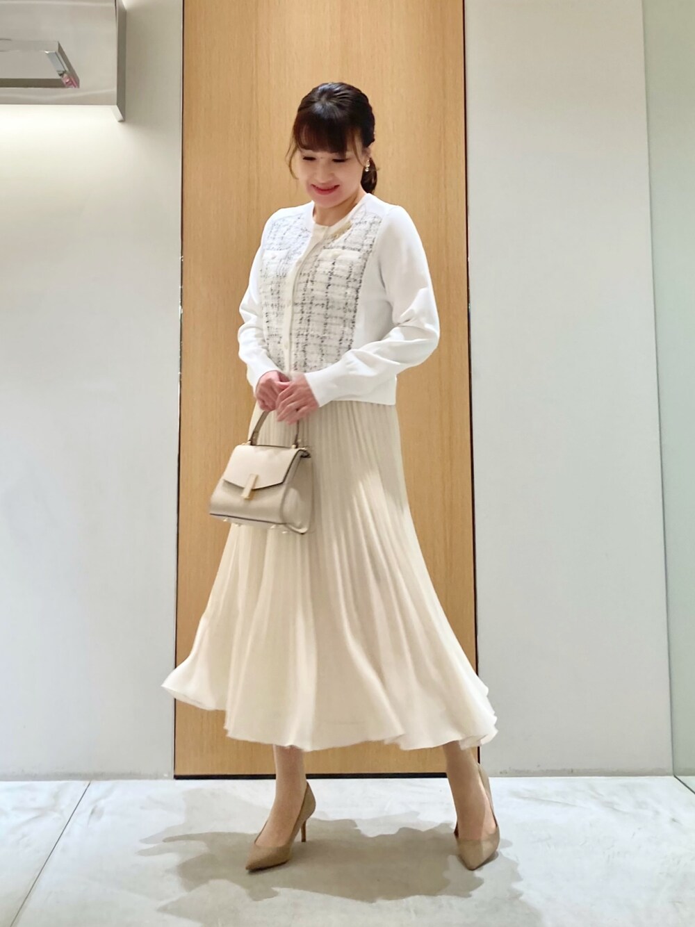 ホワイト系のカーディガン/ボレロ、ベージュ系のトートバッグ、ホワイト系のスカートを着用したレディースの冬コーディネートの1枚目の写真