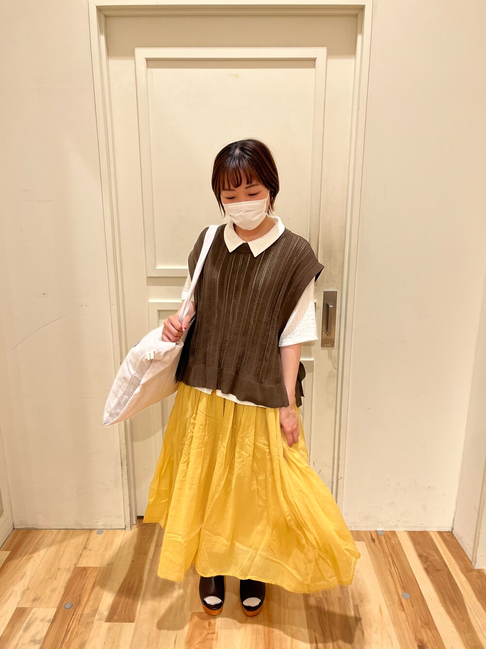 ブラウン系のベスト、ホワイト系のTシャツ/カットソー、イエロー系のスカートを着用したレディースの春コーディネートの1枚目の写真