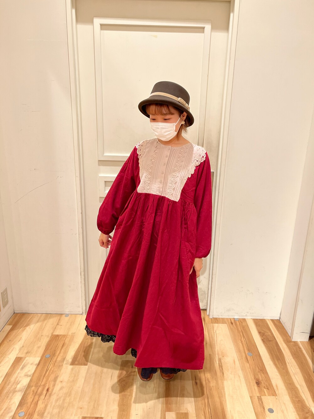 レッド系のワンピース、ブラック系のスカート、イエロー系のパンプスを着用したレディースの秋コーディネートの1枚目の写真