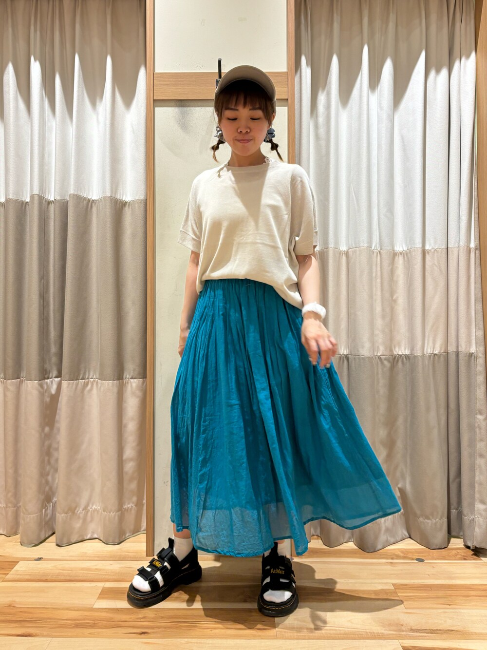 ブルー系のスカート、ブルー系のニット/セーター、ベージュ系のハットを着用したレディースの夏コーディネートの1枚目の写真