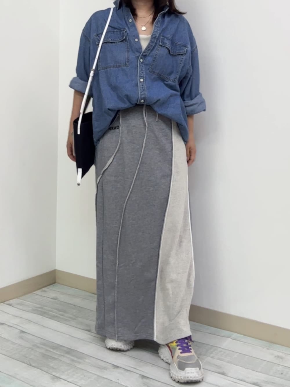 グレー系のスカート、ブルー系のシャツ/ブラウス、レッド系のスニーカーを着用したレディースの秋コーディネートの1枚目の写真