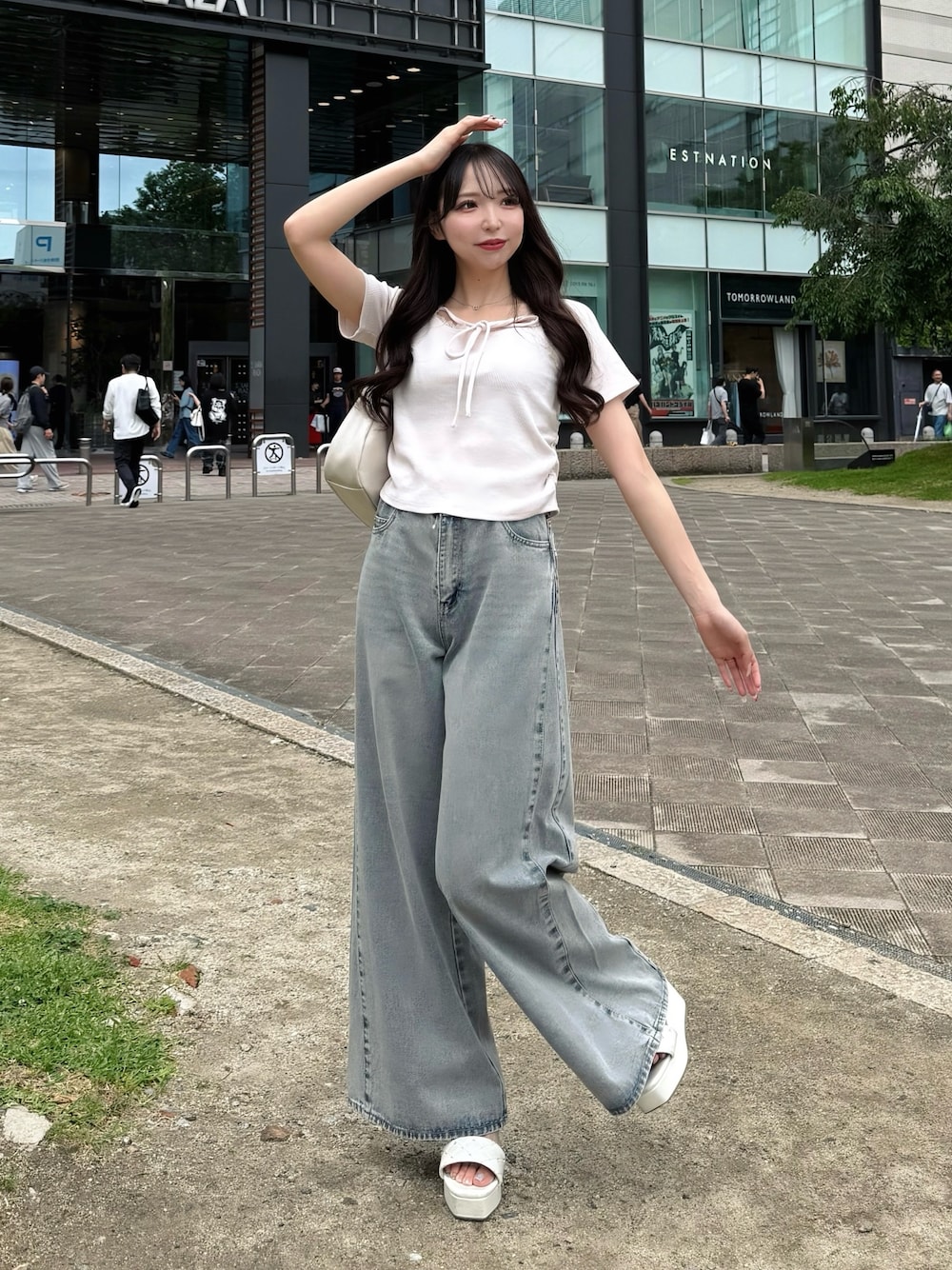 ブルー系のデニムパンツ、ピンク系のTシャツ/カットソー、ホワイト系のハンドバッグを着用したレディースの夏コーディネートの1枚目の写真