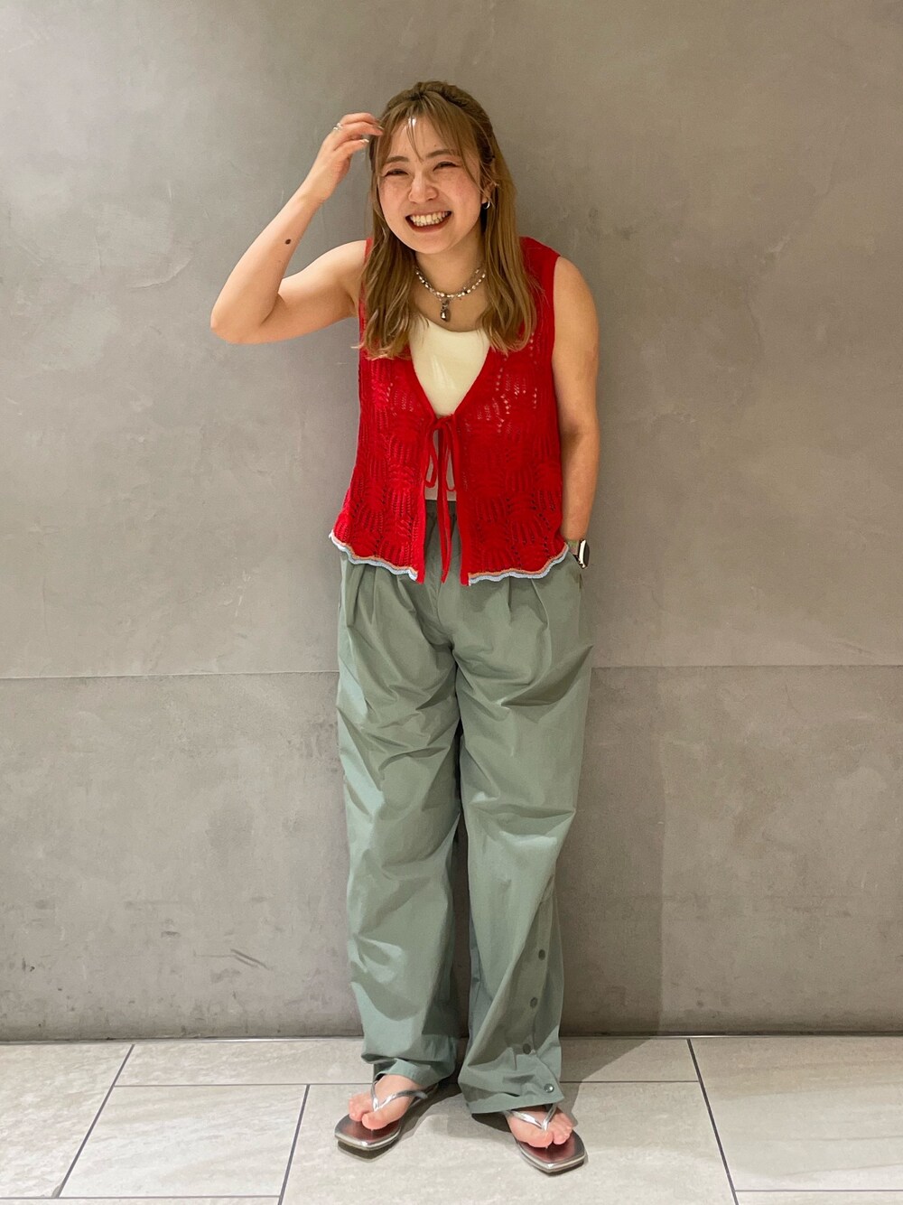 グリーン系のその他パンツ、レッド系のニット/セーター、ホワイト系のキャミソールを着用したレディースの春コーディネートの1枚目の写真