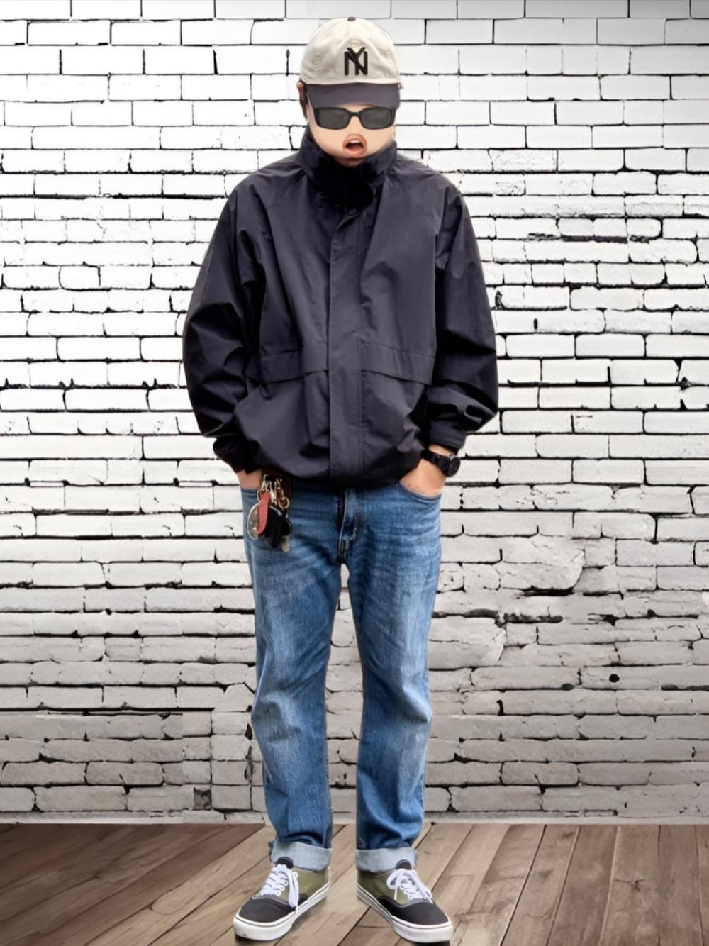 ブルー系のデニムパンツ、グリーン系のスニーカー、ブラック系のマウンテンパーカーを着用したメンズの冬コーディネートの1枚目の写真