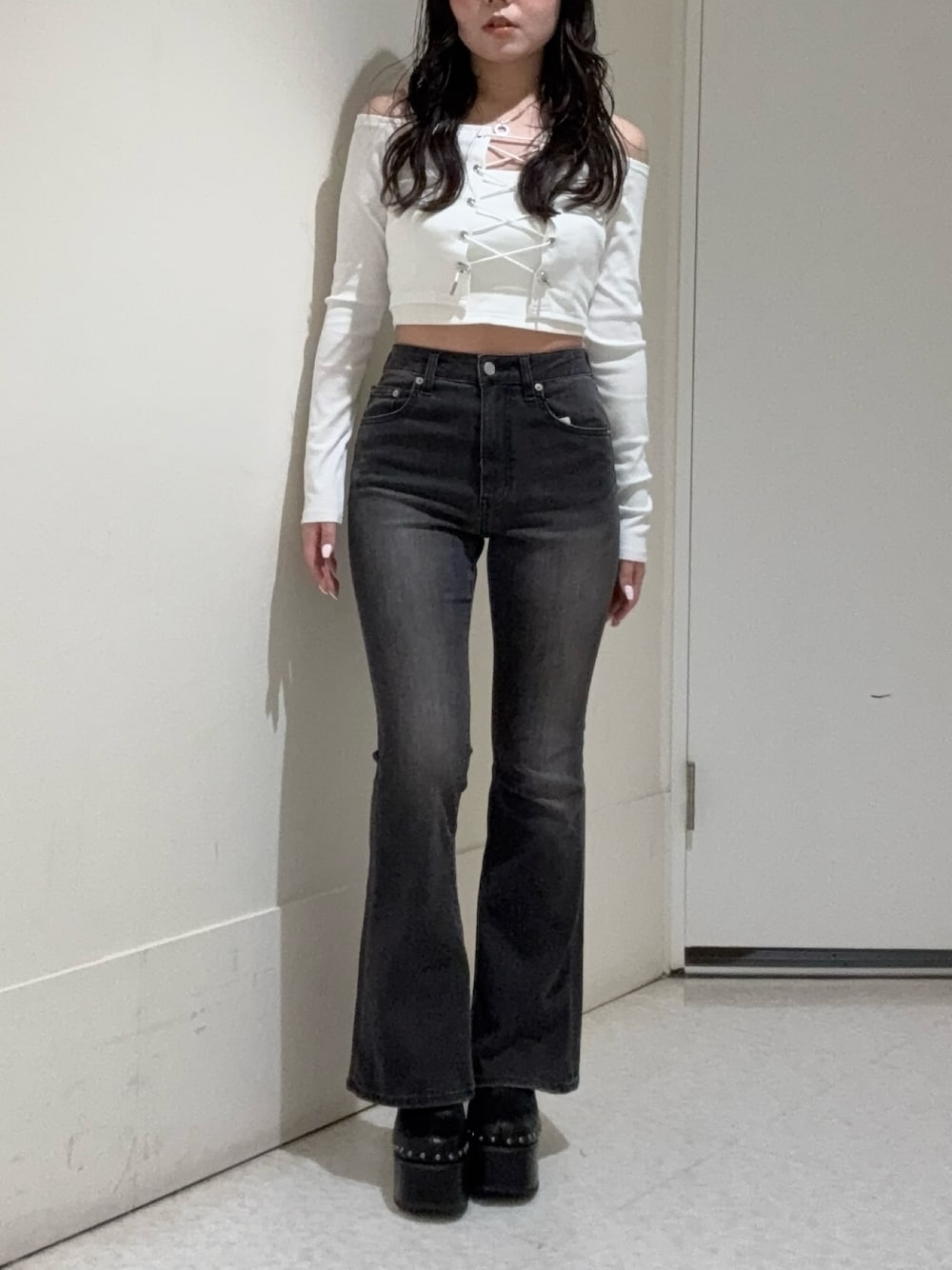 ブラック系のデニムパンツ、ホワイト系のTシャツ/カットソー、ブラック系のサンダルを着用したレディースの春コーディネートの1枚目の写真