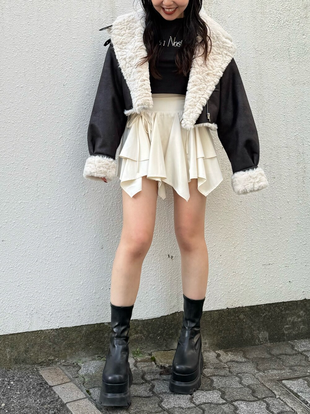 ブラック系のブーツ、ブラック系のブルゾン、ホワイト系のスカートを着用したレディースの秋コーディネートの1枚目の写真