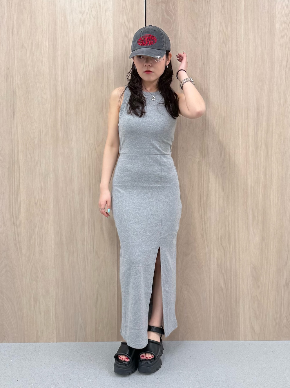 グレー系のワンピース、ブラウン系のサンダル、ブラック系のキャップを着用したレディースの春コーディネートの1枚目の写真