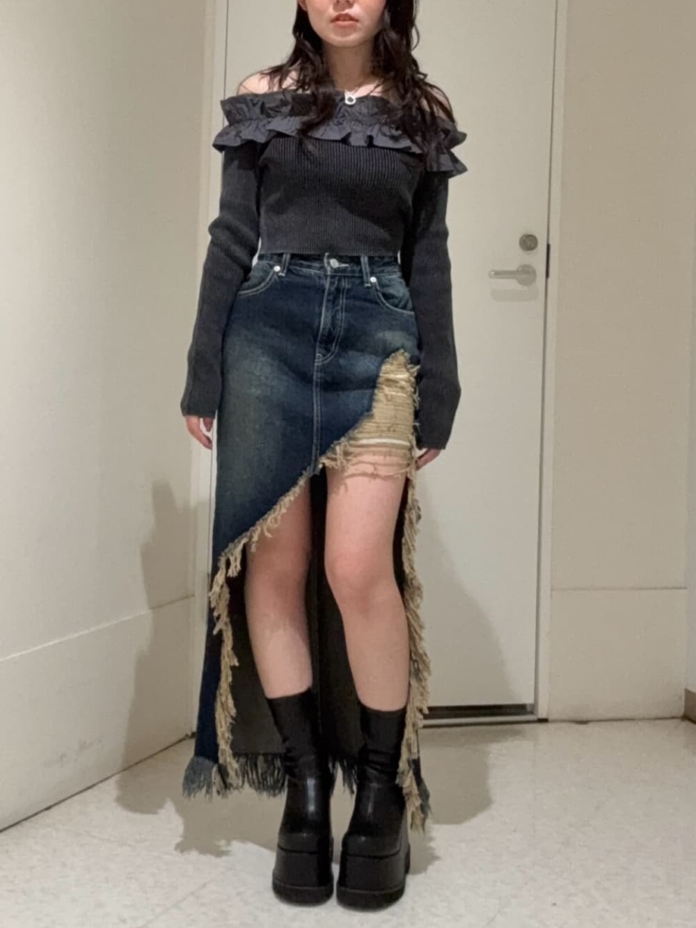 ブラック系のブーツ、ブルー系のデニムスカート、ブラック系のニット/セーターを着用したレディースの冬コーディネートの1枚目の写真