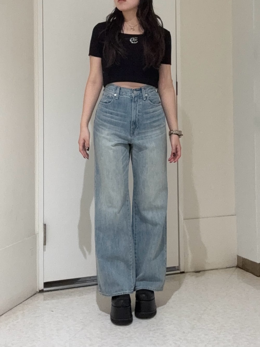 ブラック系のニット/セーター、ブルー系のデニムパンツ、ブラック系のブーツを着用したレディースの春コーディネートの1枚目の写真