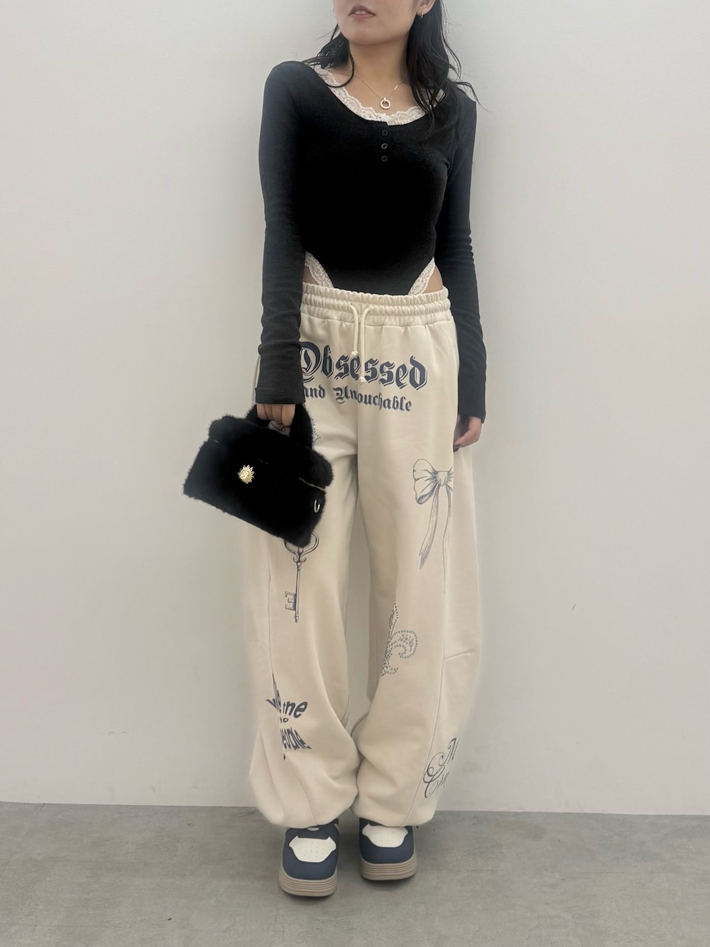 グレー系のTシャツ/カットソー、ホワイト系のスウェットパンツ、ブラック系のショルダーバッグを着用したレディースの秋コーディネートの1枚目の写真